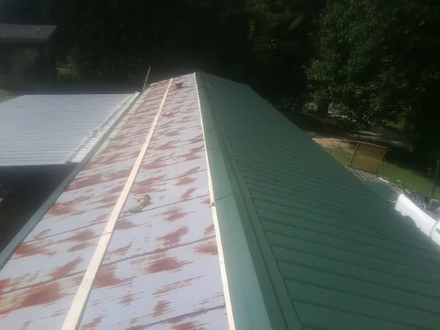 Old rusted panels beside newly installed green metal roofing — Wind Damage Roof Repair by Roofing Brothers in Spurgeon