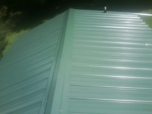 New green metal panels meeting at the ridge of a roof — Flat Roof Repair work by our crew in Spurgeon