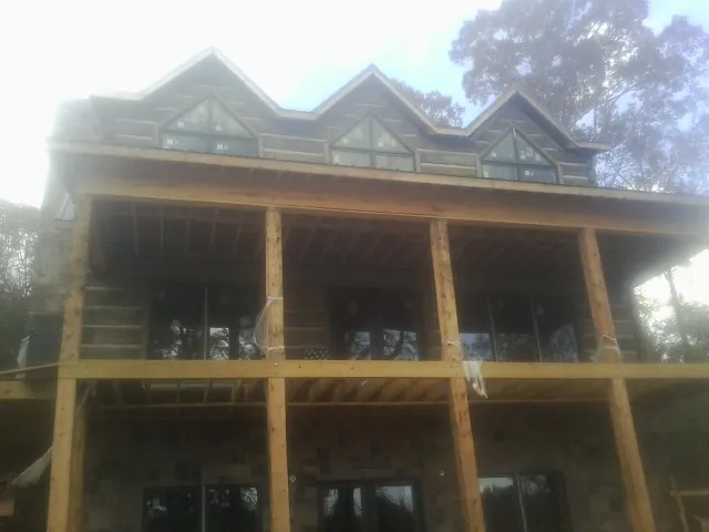 Dormers and porch framing on a large log home under construction — Roof Coating work by our crew in Spurgeon