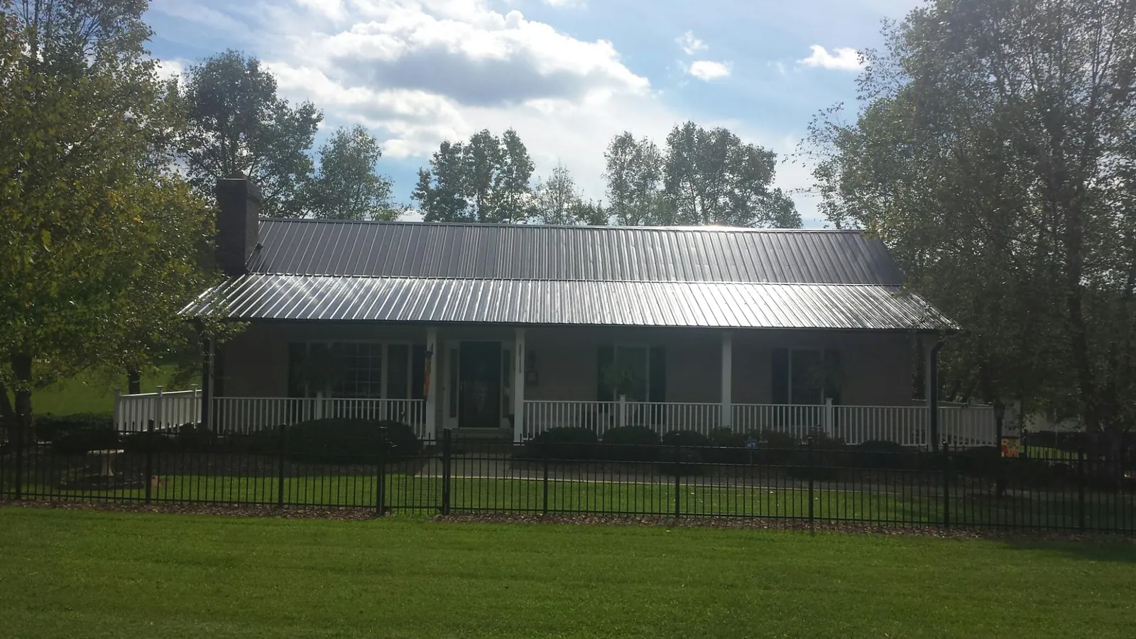 Gray metal roof on a brick ranch with a full width front porch — Gutter Guard Installation work by our crew in Spurgeon