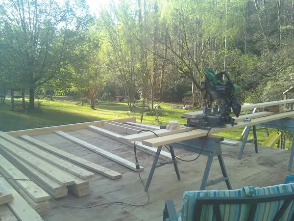 Miter saw and framing lumber on a deck under construction in Spurgeon