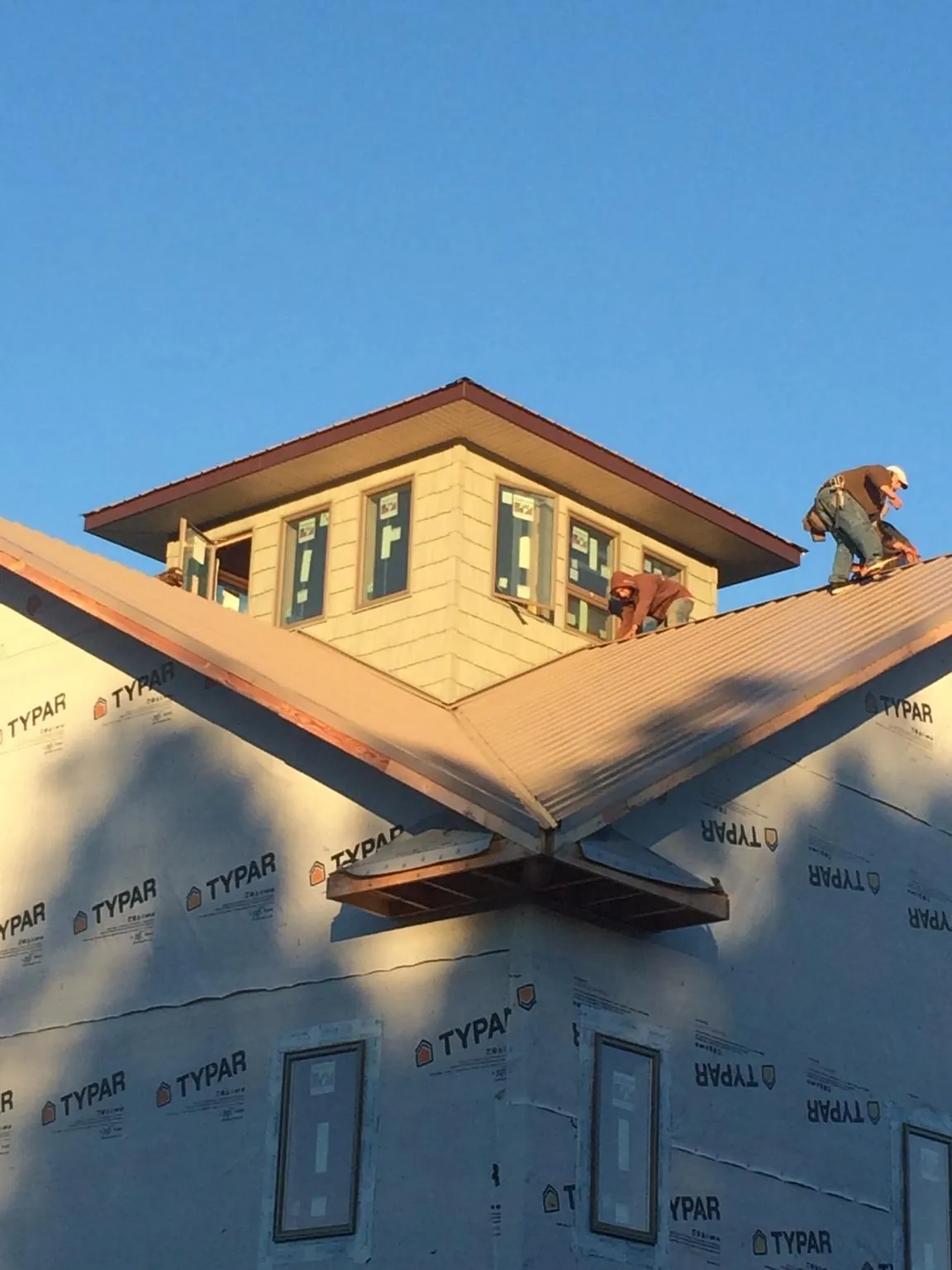 Roofers working around a rooftop cupola on a new metal roof at sunset — Roof Waterproofing in Spurgeon by Roofing Brothers